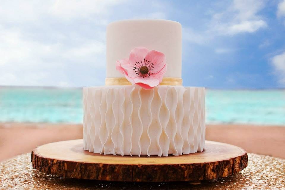 Textured white cake with a sugar anemone on a beach